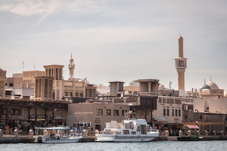 Scenic view of Dubai Creek with boats and traditional Middle Eastern architecture in the background.